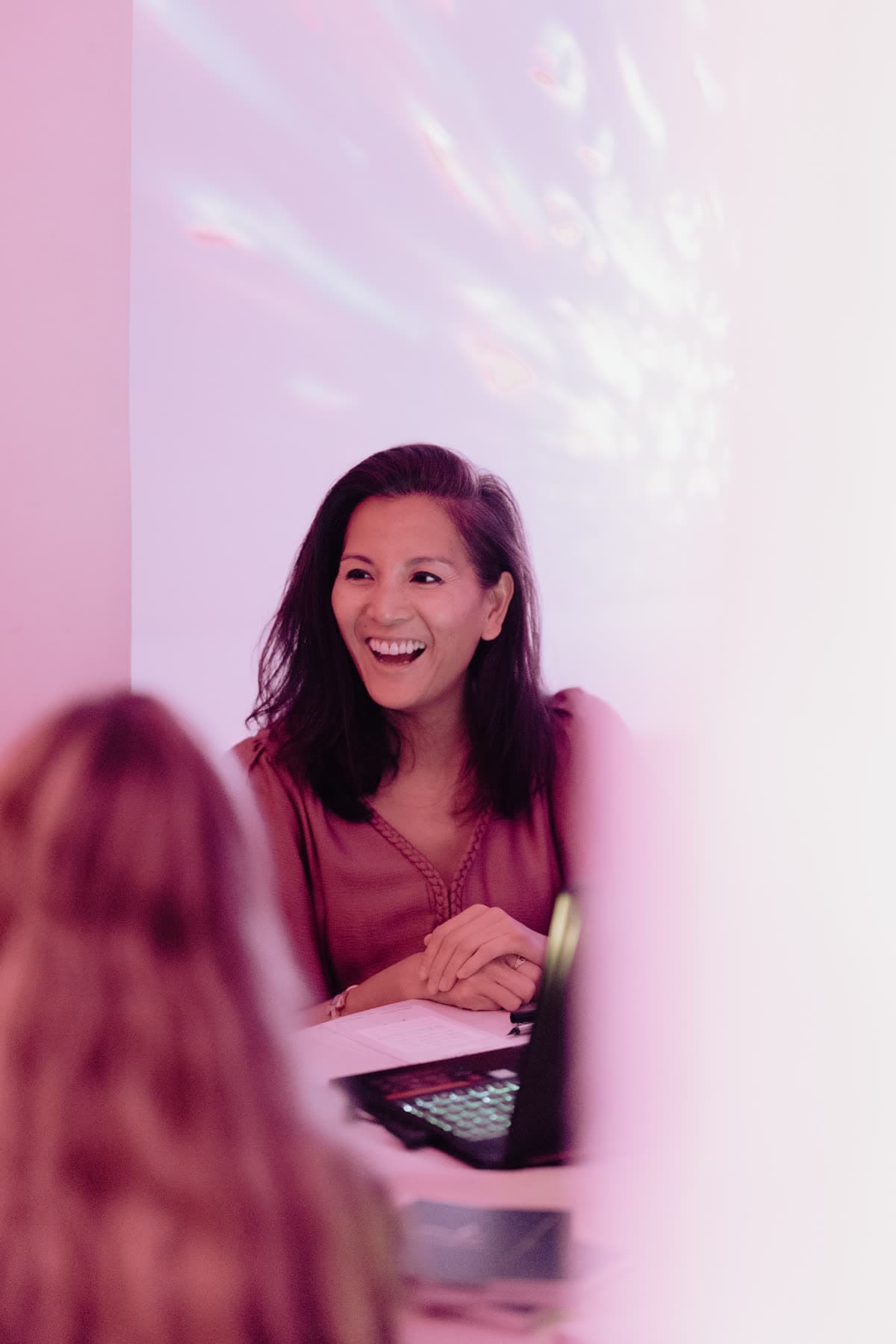 A speed consult: Marie-Ange laughing behind her laptop, across from a guest