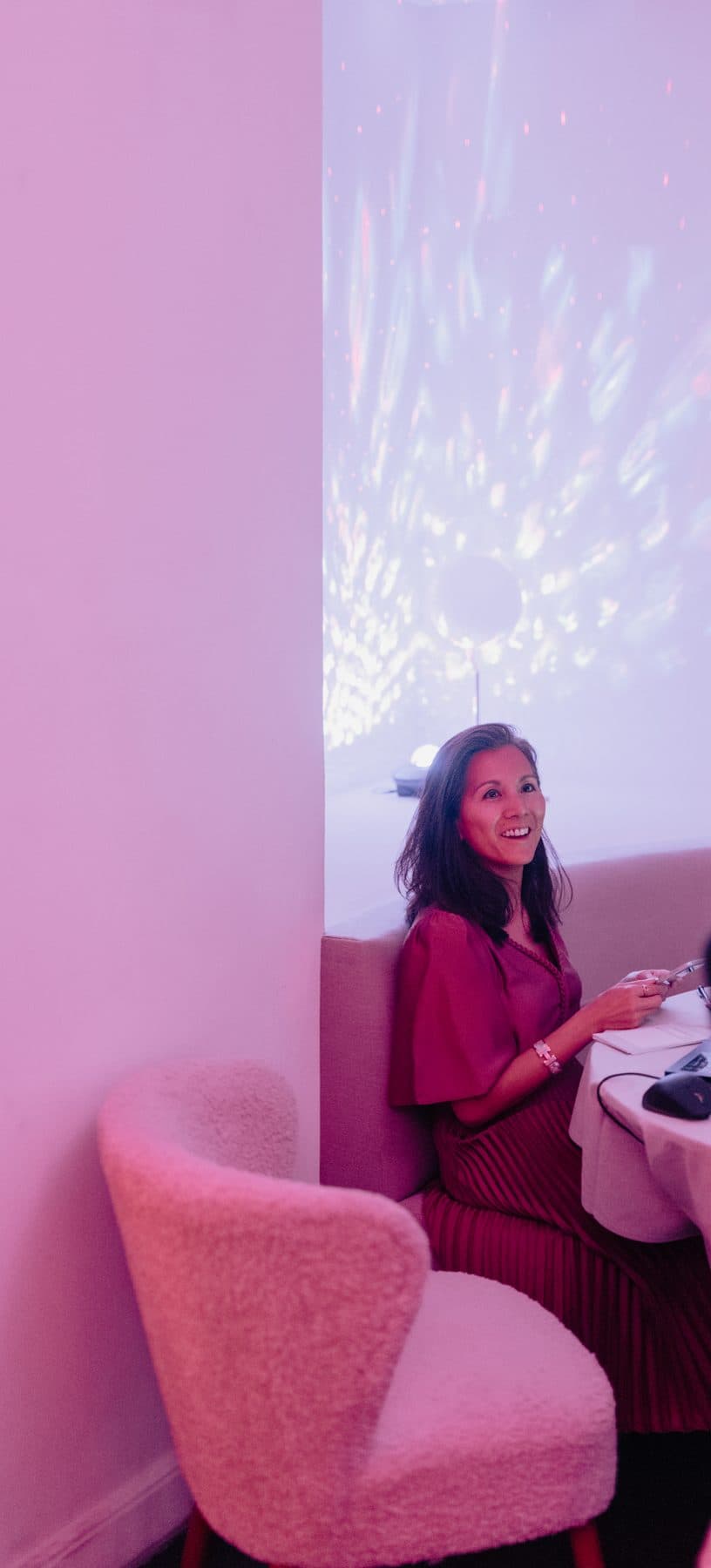 Marie-Ange at her table with her laptop under a starry projection